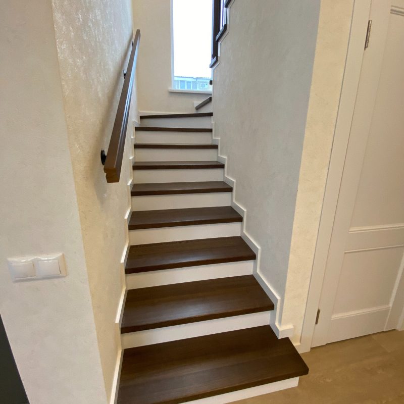 Отделка лестницы из бетона с забежными ступенями ясенем темного цвета
