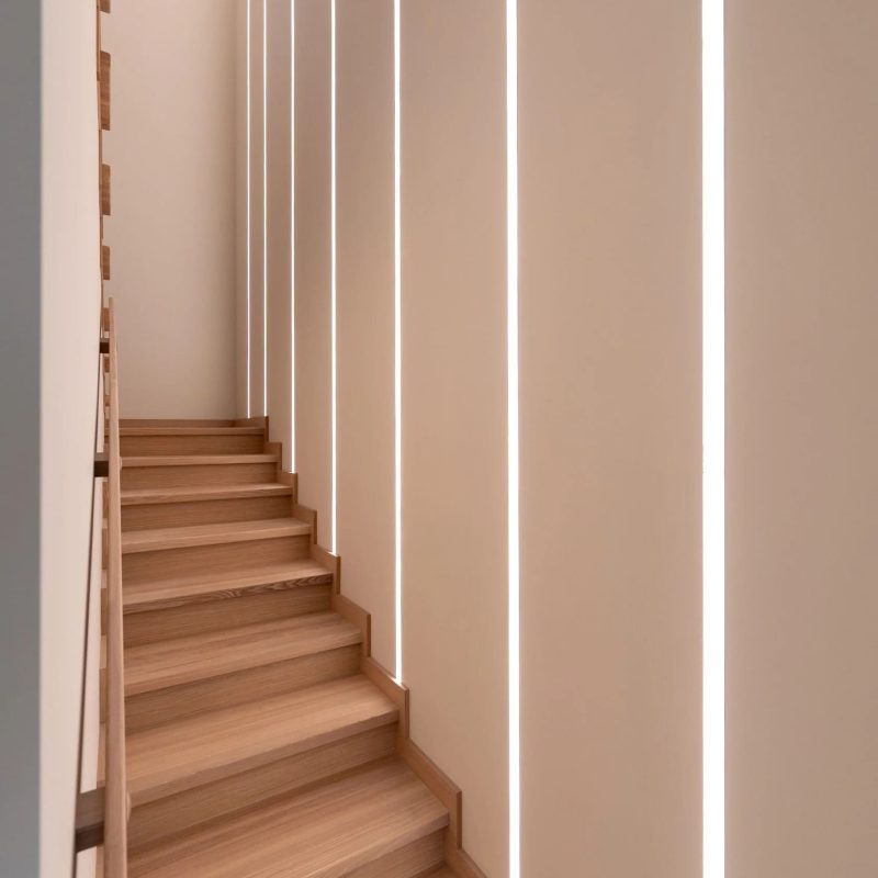 Облицовка лестницы на металлокаркасе ясенем с подсветкой на стене